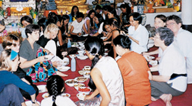 Scarboro missioners Dorothy Novak, seated first on the right, and Sr.  Fernande Barnabé, third on the left, enjoy a meal with foreign volunteers at a Buddhist temple in Pattaya, Thailand.