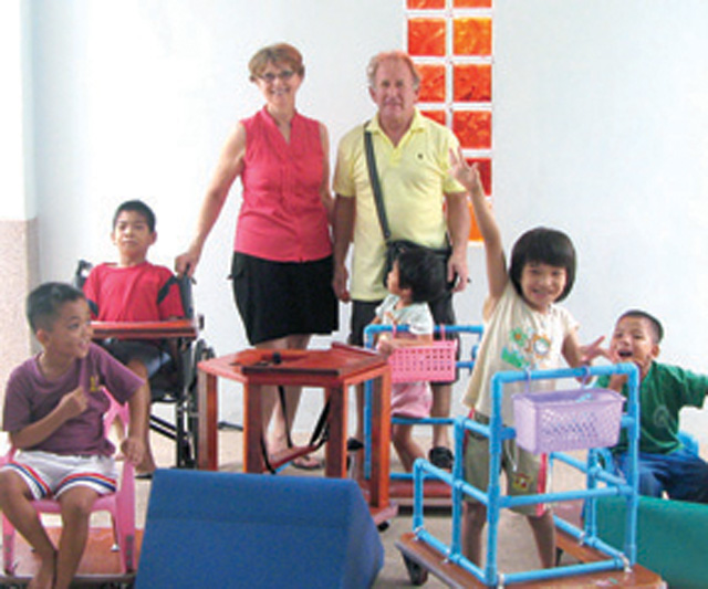 Anne & Glenn Harty with children at the Camillian Social Center in Chiang Rai that provides schooling to ill tribe children, including children with disabilities. The Centre utilizes some of the mobility and exercise aids that Glenn has made. Anne teaches as well as assists with physio and occupational therapy.
