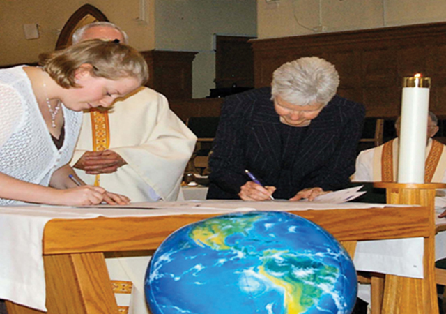 At her missioning ceremony, Leslie Paranuik (left) signs her three year contract with Scarboro, witnessed by Kate O’Donnell